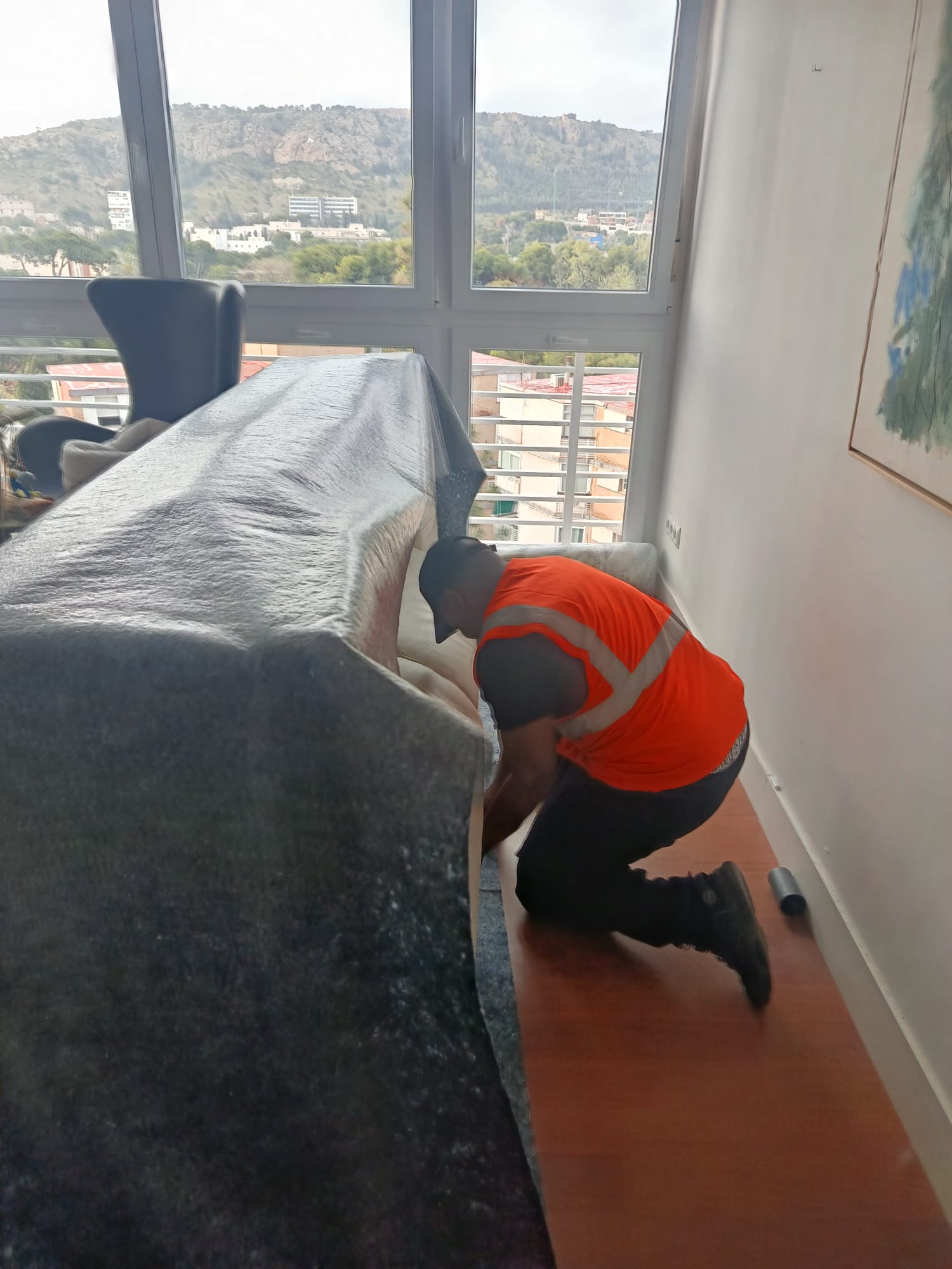 Operario protegiendo un sofá con manta acolchada antes del traslado