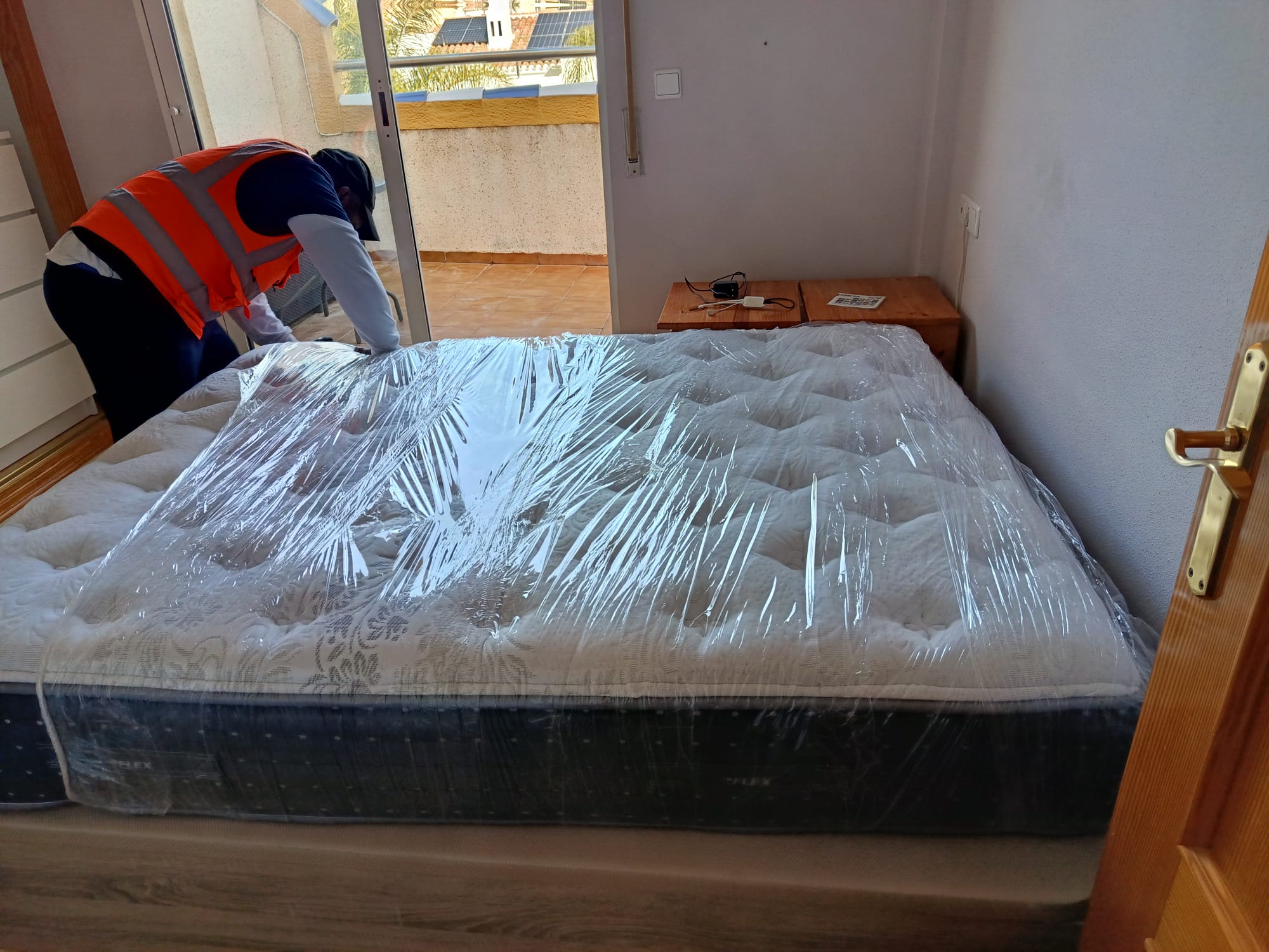 Operario colocando un colchón Flex protegido con plástico sobre una cama